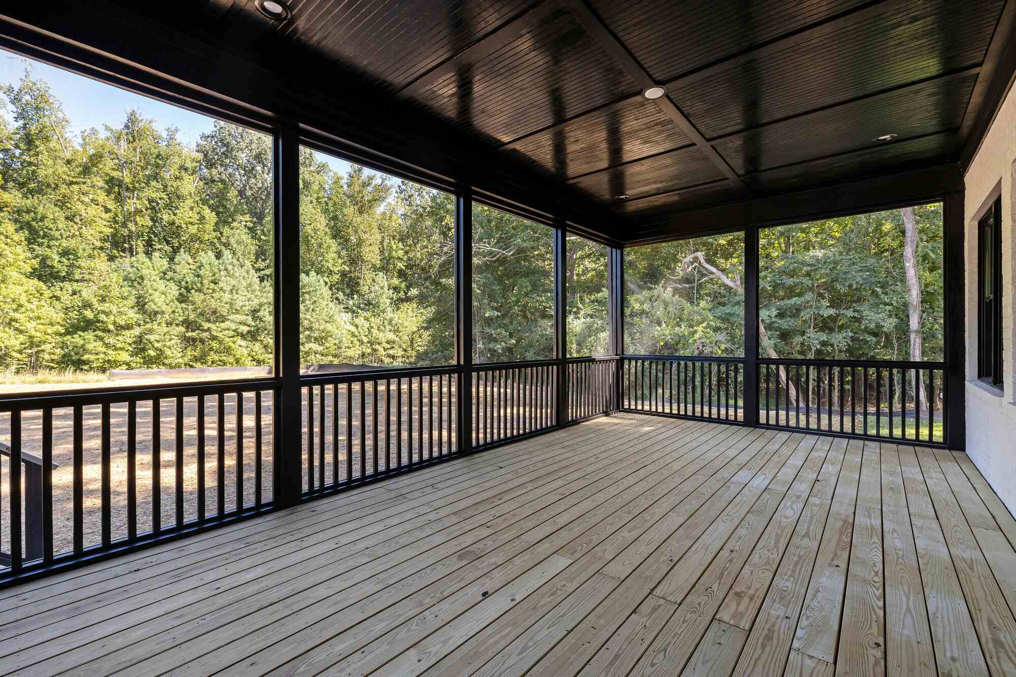 Black-trimmed screened-in deck with wood flooring in a Metzler Construction custom home in Perkasie, PA - Stock Image