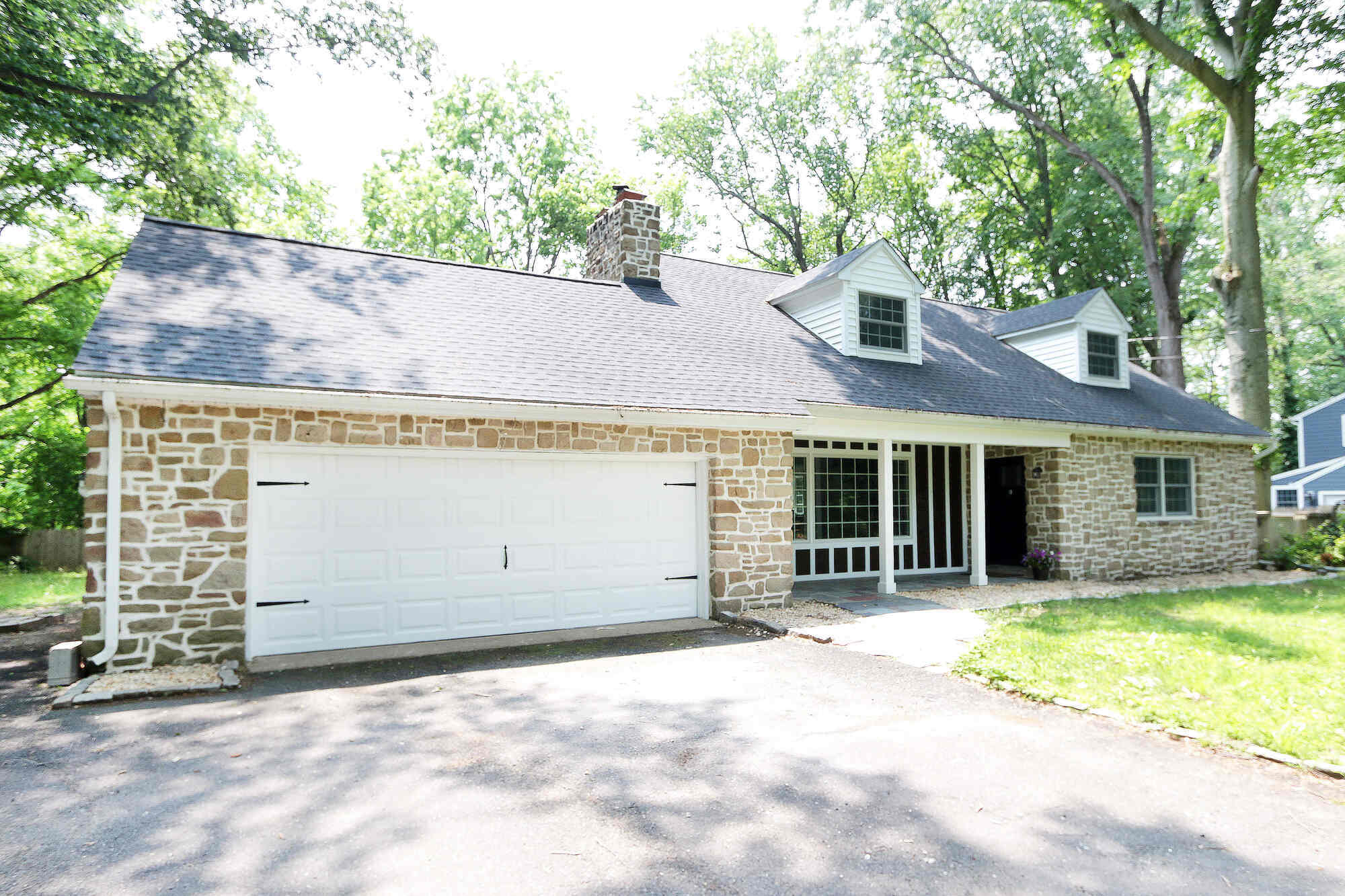 Renovated front view of custom home featuring stone facade and new roof in Perkasie, PA by Metzler Construction
