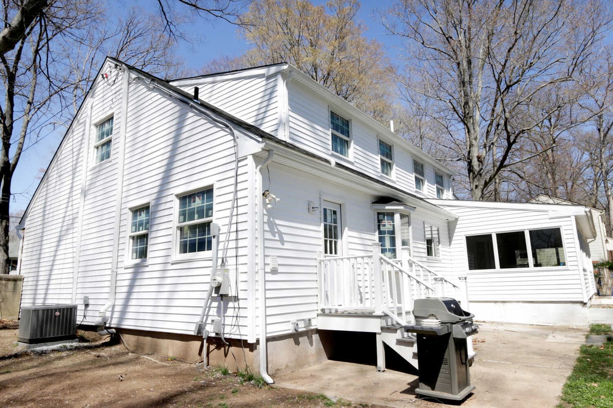 Exterior back view of white siding custom home with small deck in Perkasie, PA by Metzler Construction