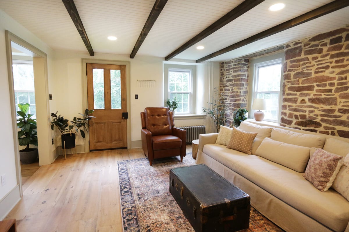 Custom farmhouse living room renovation with wood door and cozy decor in Perkasie, PA by Metzler Construction