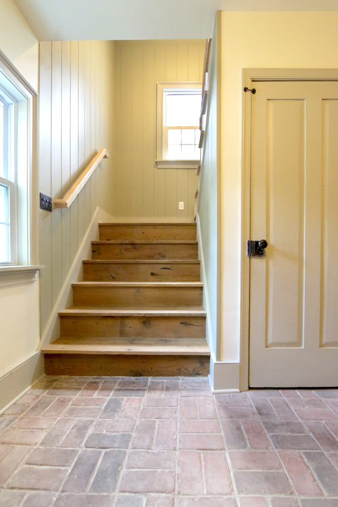 Entryway staircase remodel with natural wood treads and brick flooring by Metzler Construction in Perkasie, PA