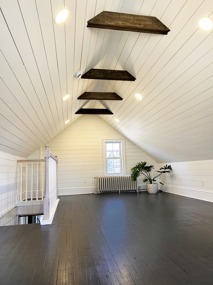 Finished attic renovation with white shiplap walls and dark wood beams by Metzler Construction in Perkasie, PA