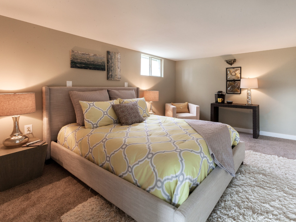 Basement bedroom with natural light and cozy furnishings in a Metzler Construction home in Perkasie, PA - Stock Image
