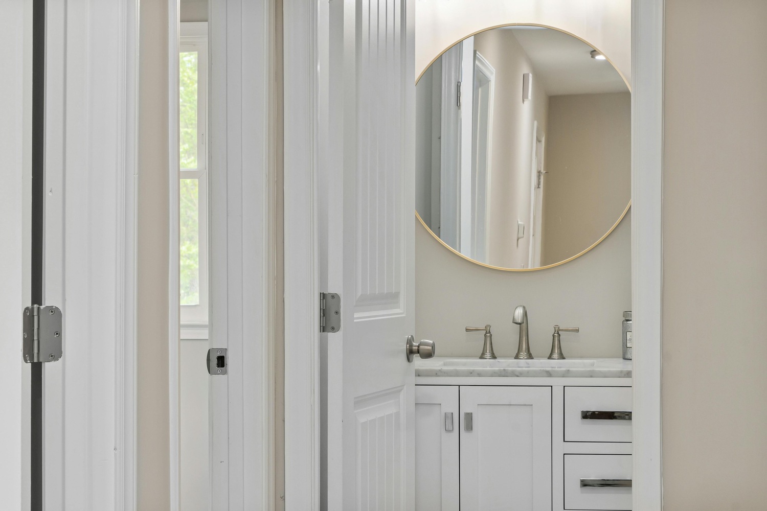 Small bathroom with round mirror and chrome fixtures in a Perkasie custom home by Metzler Construction - Stock Image