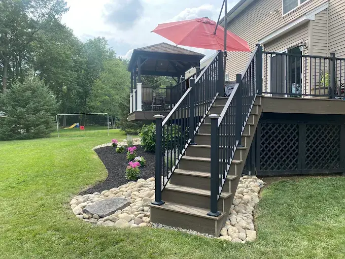 Composite decking stairs with black railing by Metzler Construction