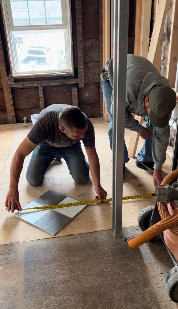 Member employees measure tile flooring