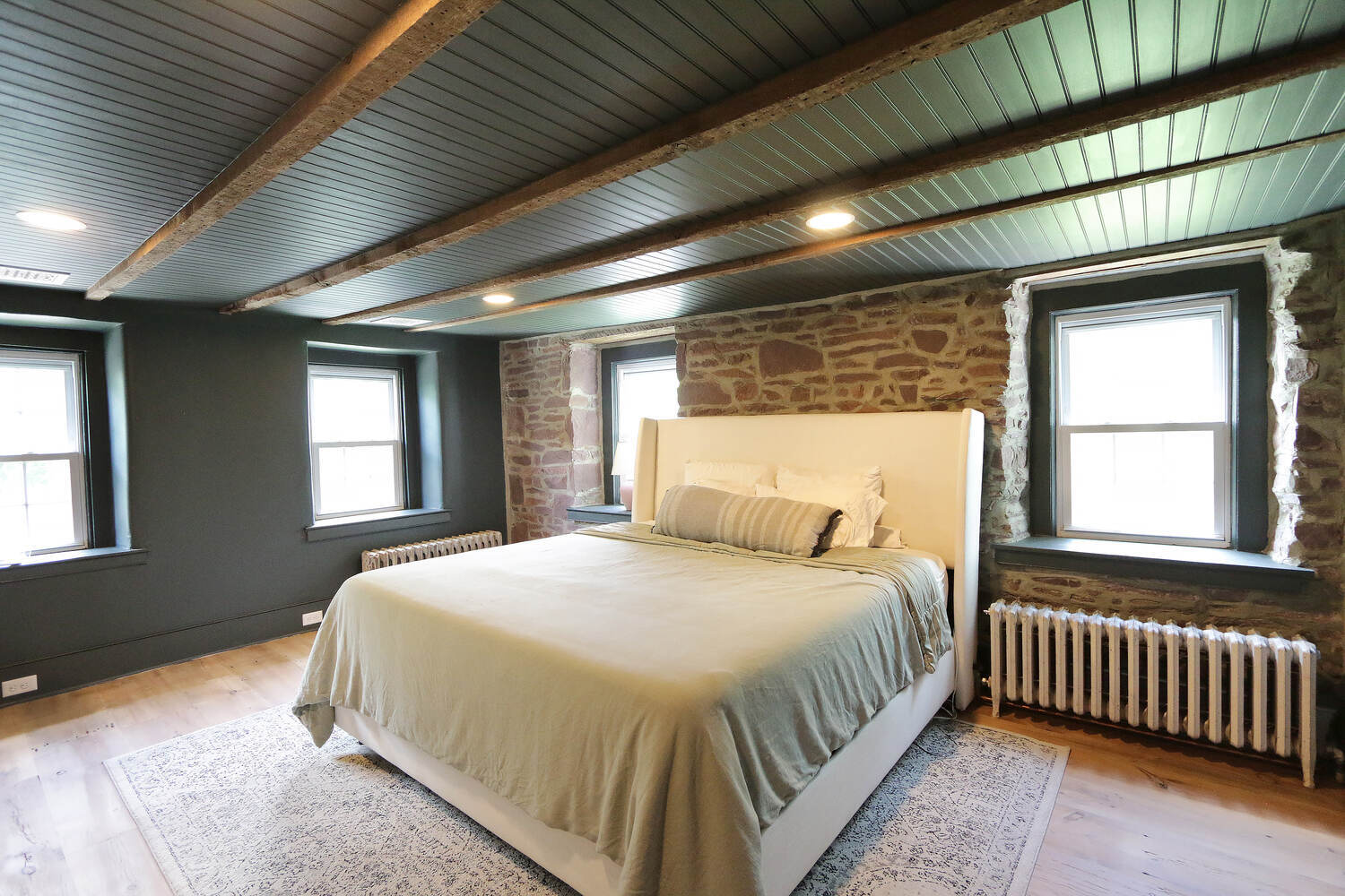 Custom bedroom remodel with exposed stone walls and neutral tones by Metzler Construction in Perkasie, PA