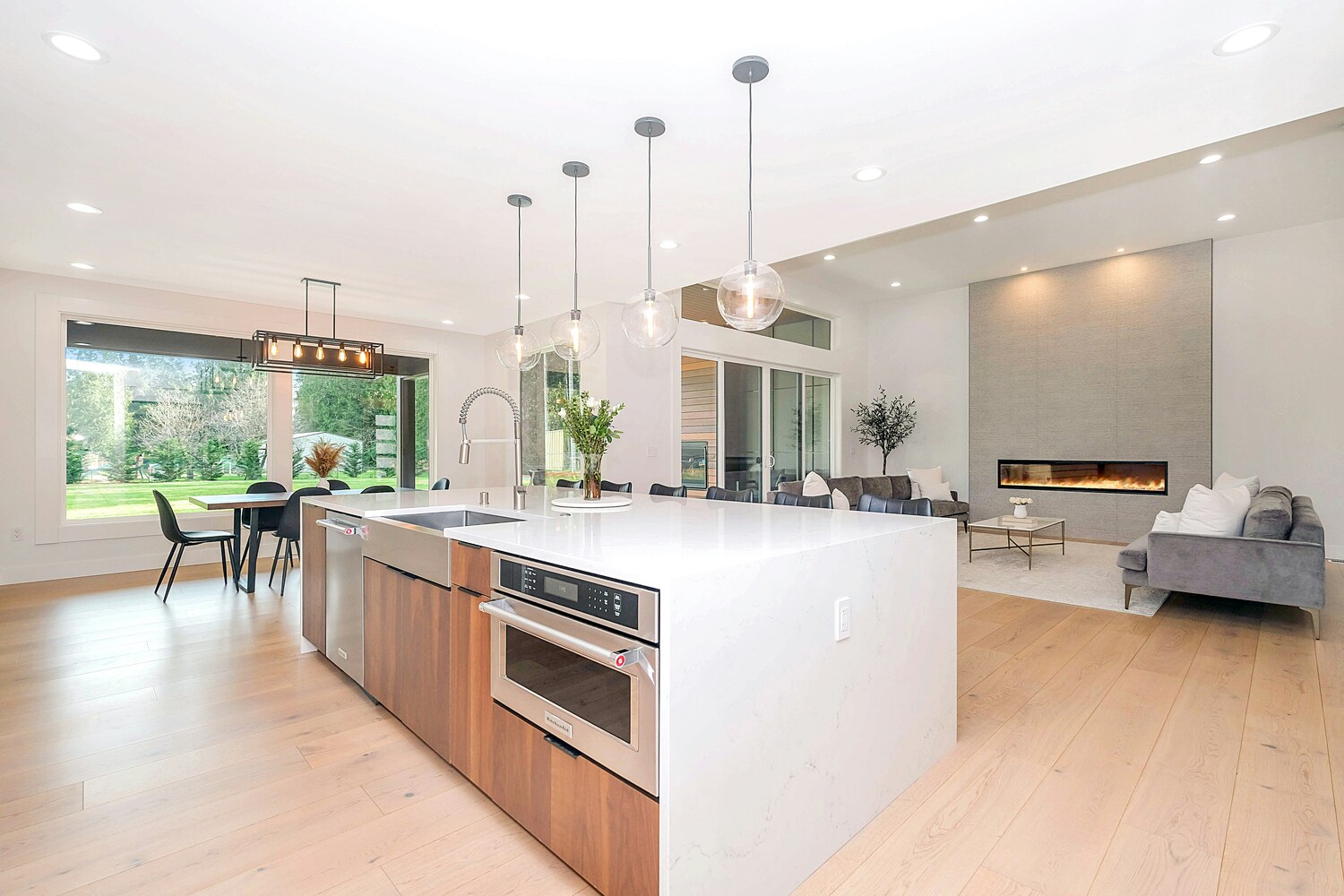 Open-concept kitchen and living room with modern fireplace in Metzler Construction custom home in Perkasie, PA - Stock Image